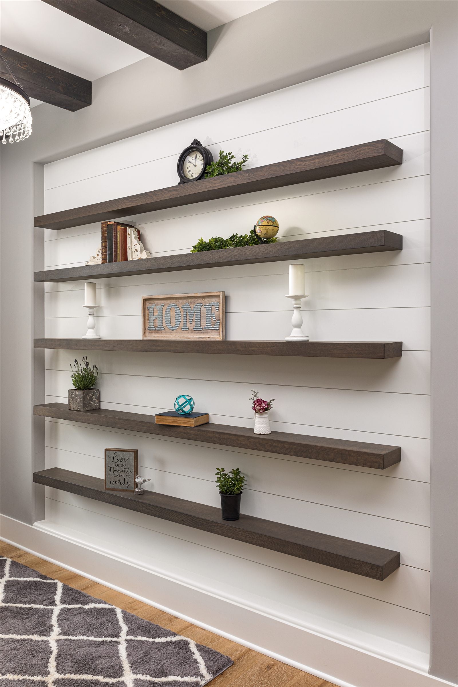 Styled shiplap entryway with five dark-stained floating shelves, books, plants, candles, and a HOME sign